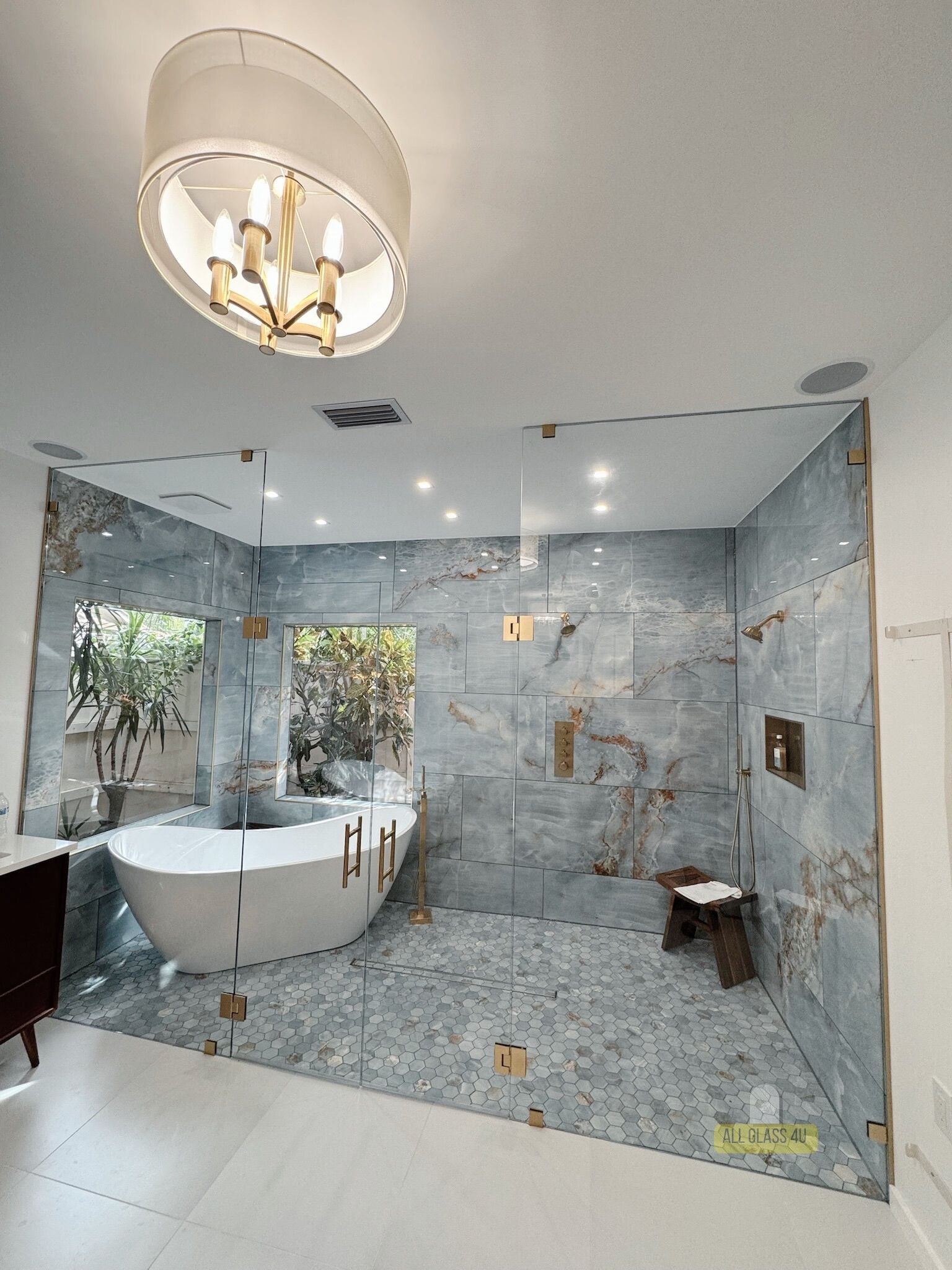 Frameless glass enclosure with brushed-gold hardware around a soaking tub and walk-in shower